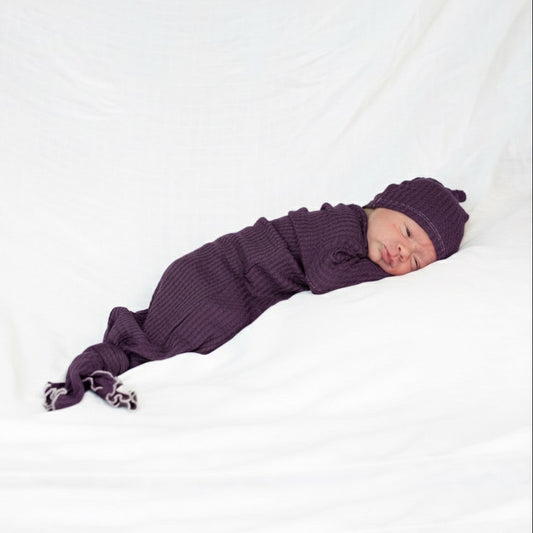 Newborn baby in a purple outfit and hat