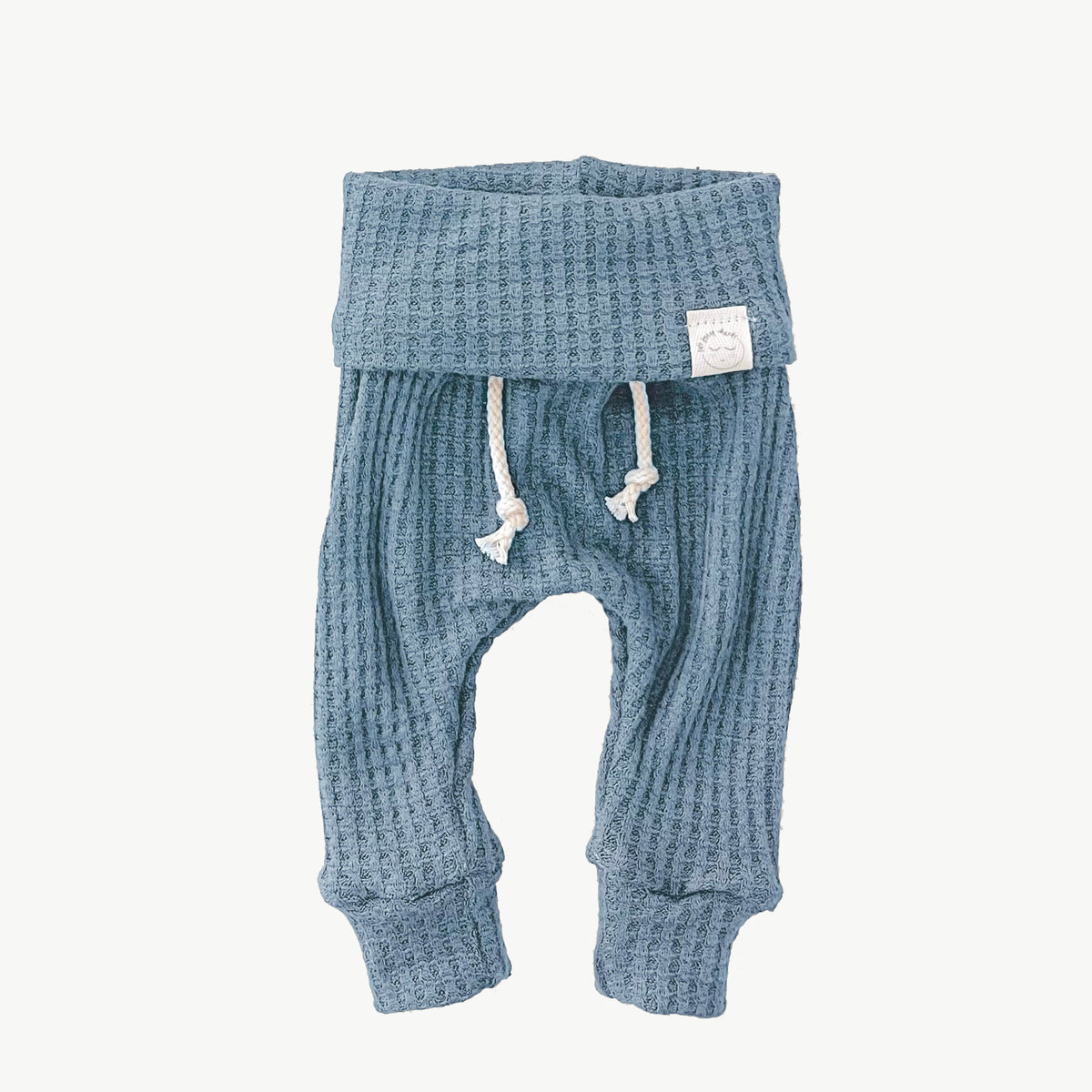 A pair of baby blue waffle-knit baby pants with a drawstring waist and ankle cuffs