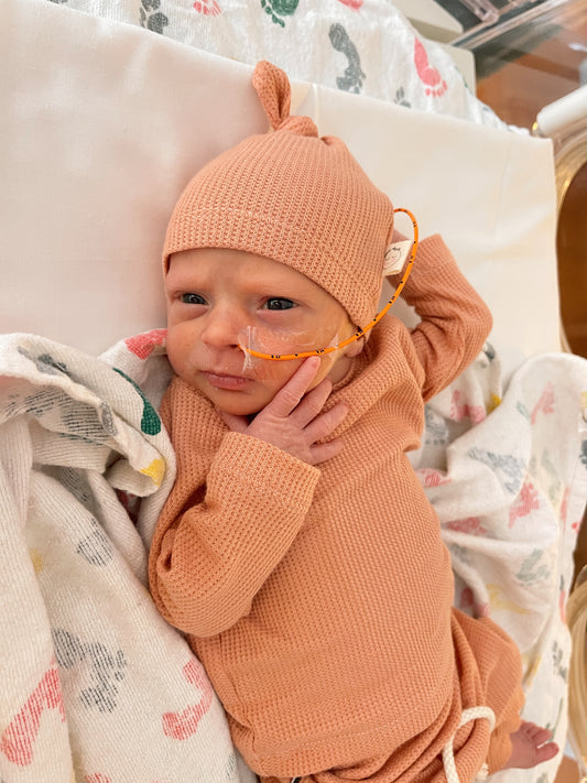 baby girl wearing peach color hat, shirt and pants in the hospital