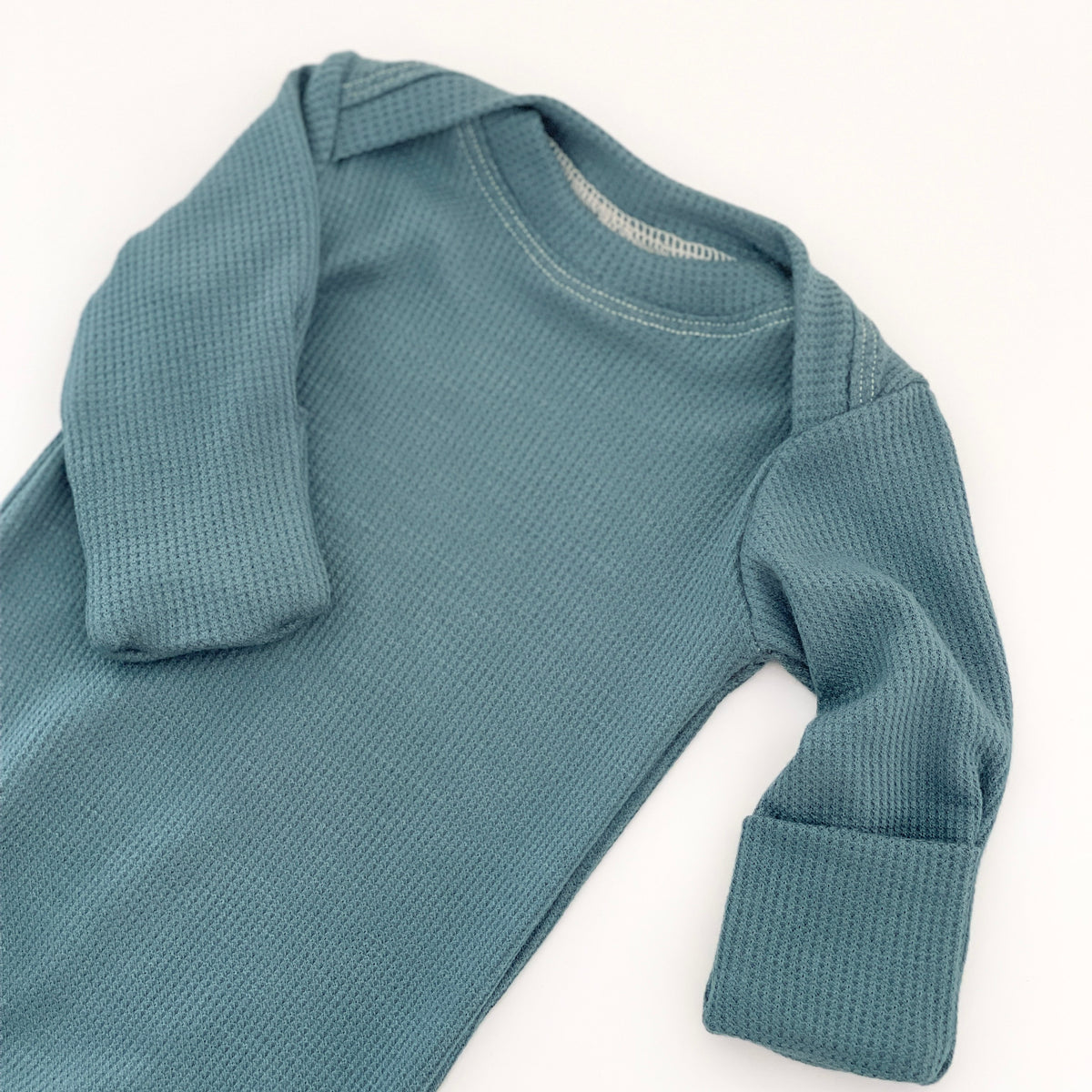 A long-sleeve waffle-knit baby gown in a muted slate blue color,