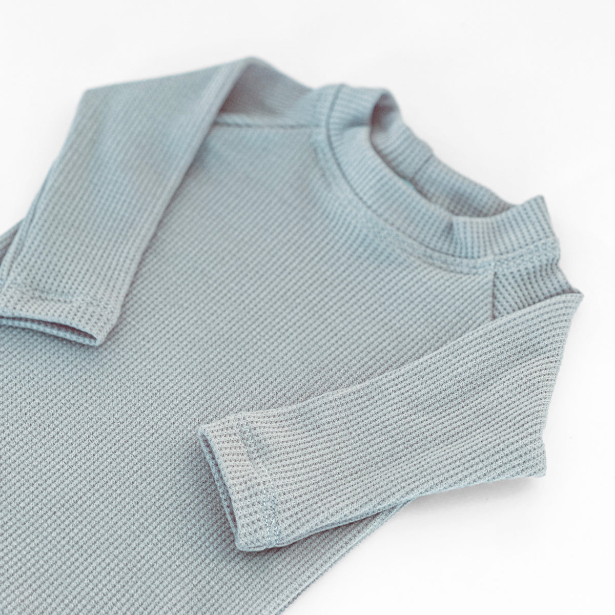A close-up of a light blue thermal knit long-sleeve top with a crew neck