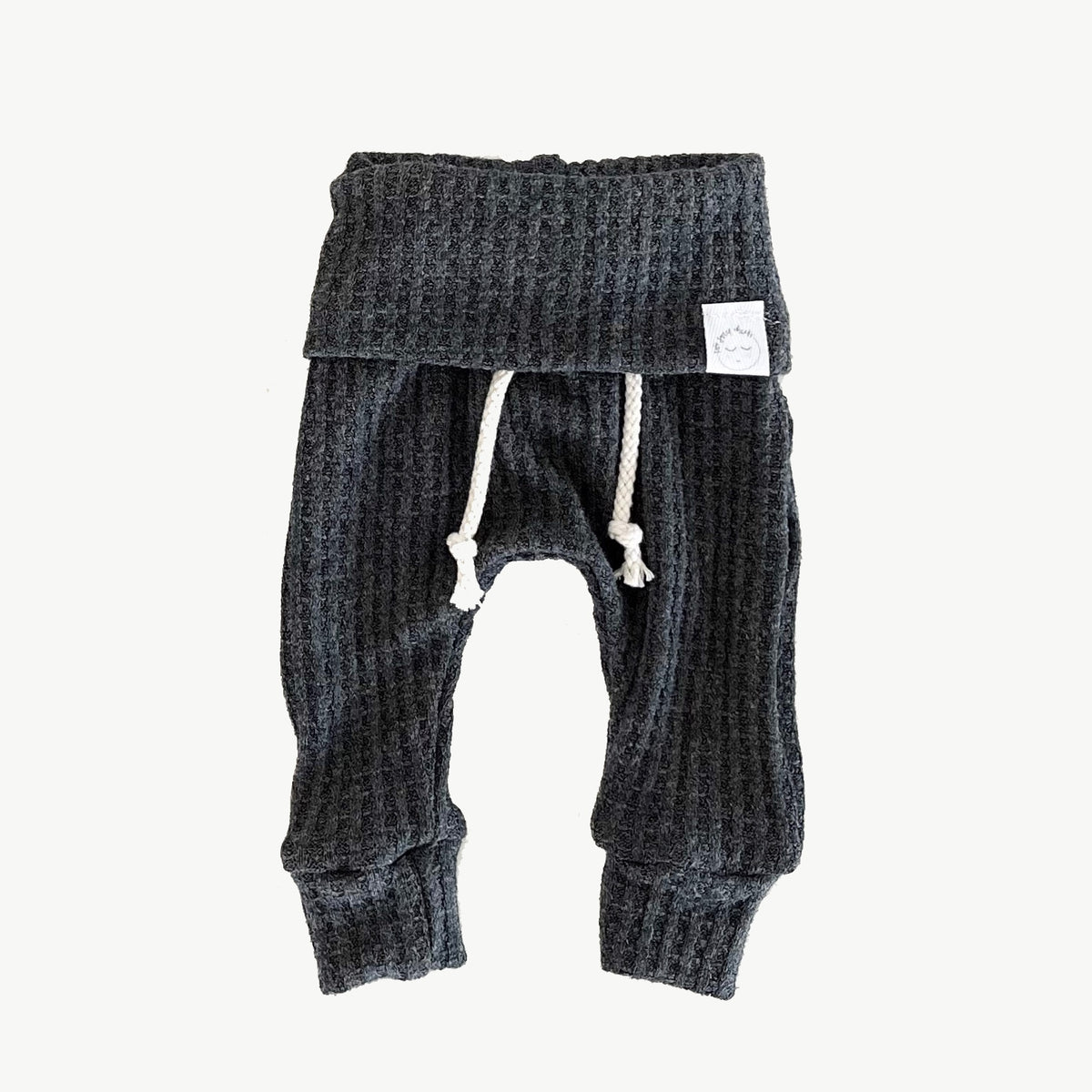 A pair of charcoal gray waffle-knit baby pants with a drawstring waist and ankle cuffs
