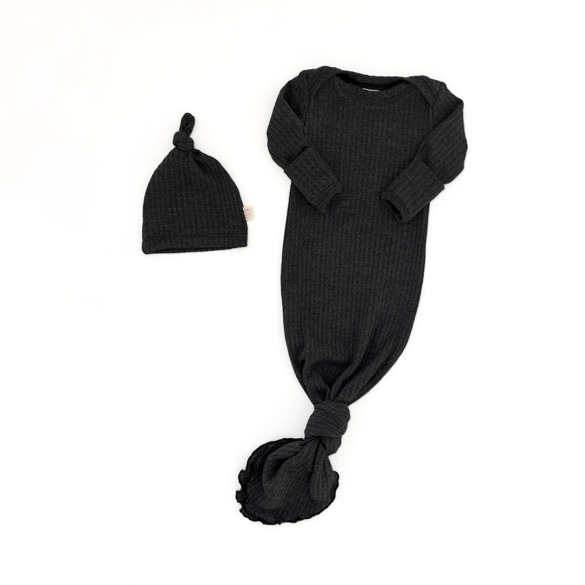 A black ribbed knit baby sleep sack with long sleeves and a tied knot