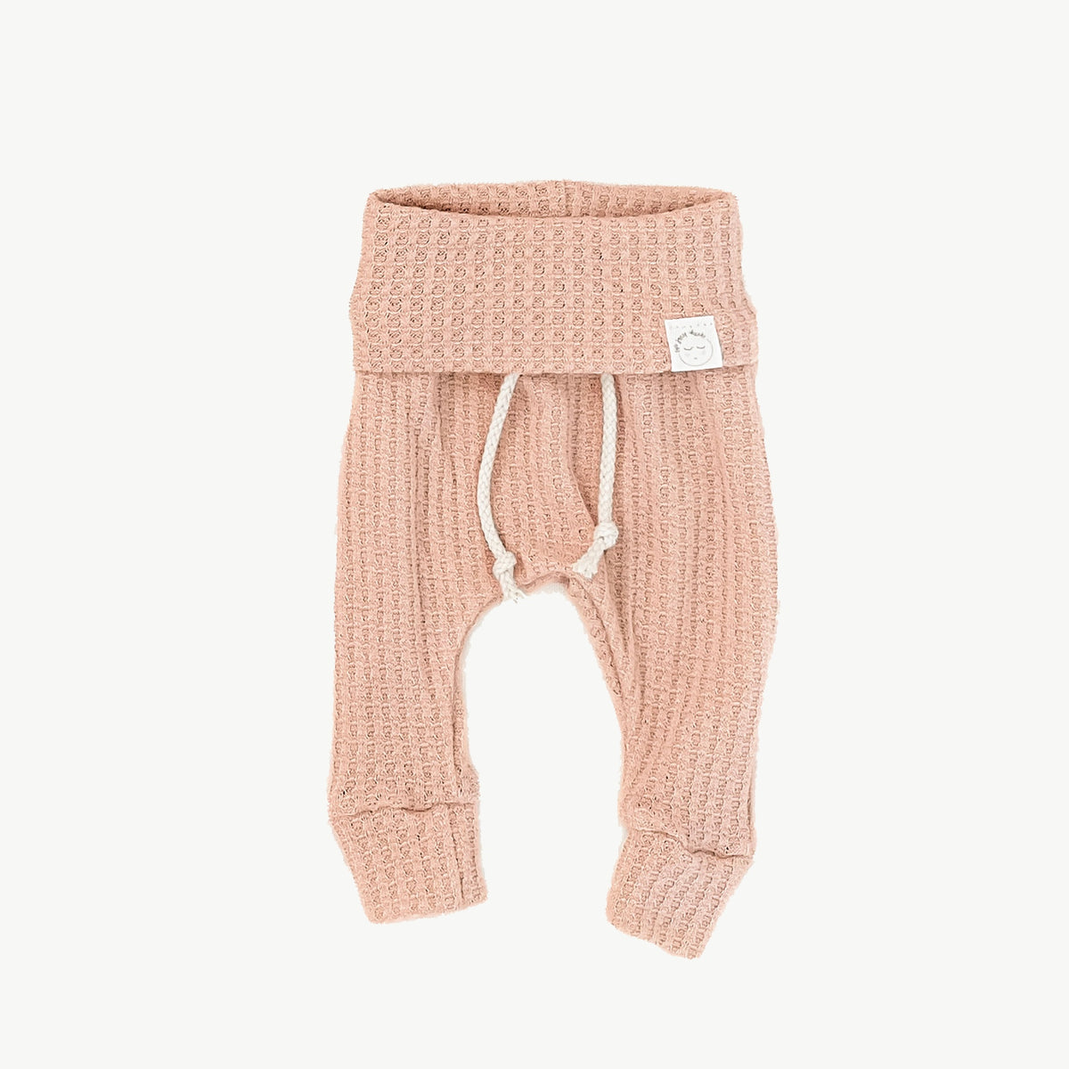 A pair of muted pink waffle-knit baby pants with a drawstring waist and ankle cuffs