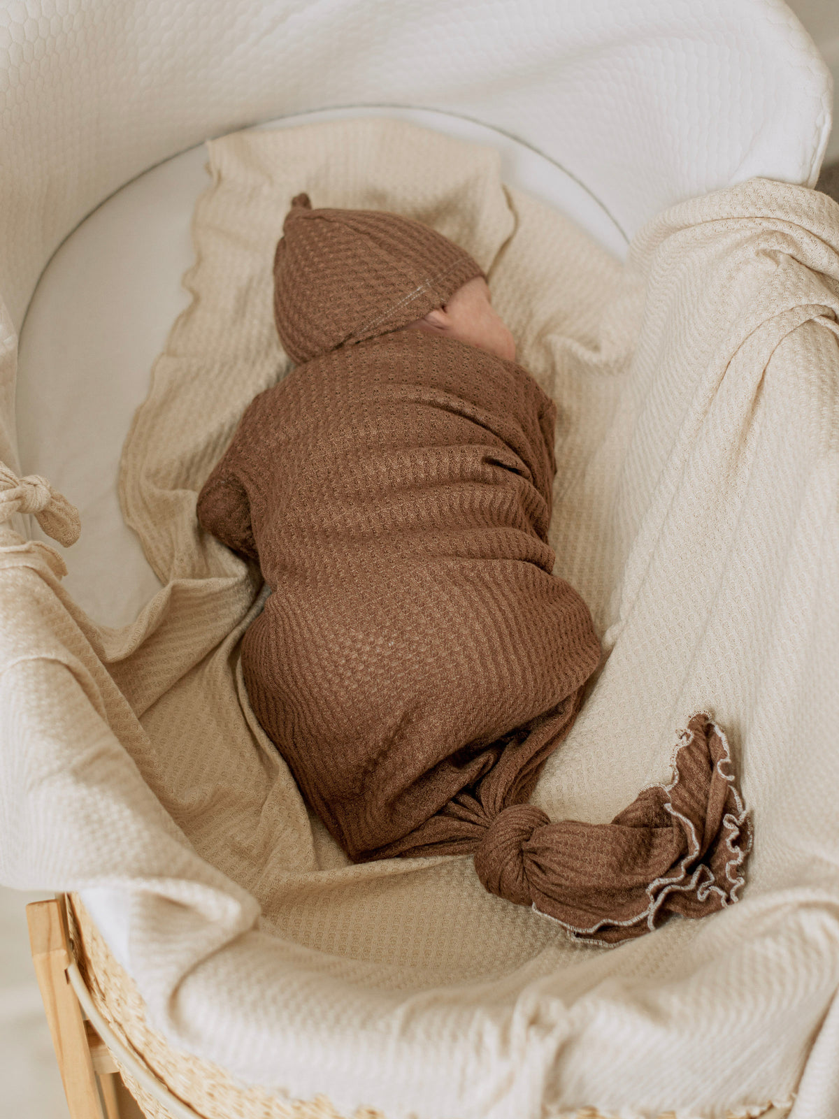 baby boy sleeping in a bassinet with a knotted gown