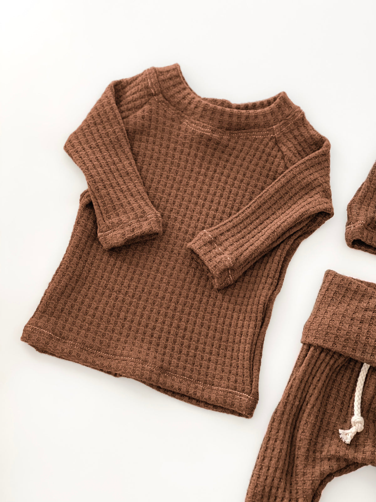 A baby waffle-knit two-piece clothing set in a warm brown color, featuring a long-sleeve top and matching bottoms