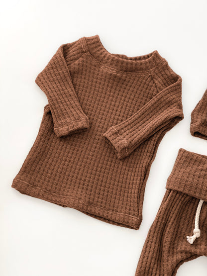 A baby waffle-knit two-piece clothing set in a warm brown color, featuring a long-sleeve top and matching bottoms
