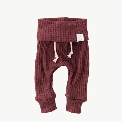 A pair of cranberry waffle-knit baby pants with a drawstring waist and ankle cuffs