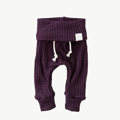 A pair of purple waffle-knit baby pants with a drawstring waist and ankle cuffs