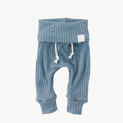 A pair of baby blue waffle-knit baby pants with a drawstring waist and ankle cuffs