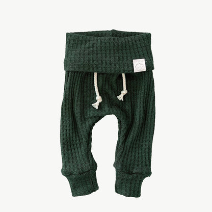 A pair of pine green waffle-knit baby pants with a drawstring waist and ankle cuffs