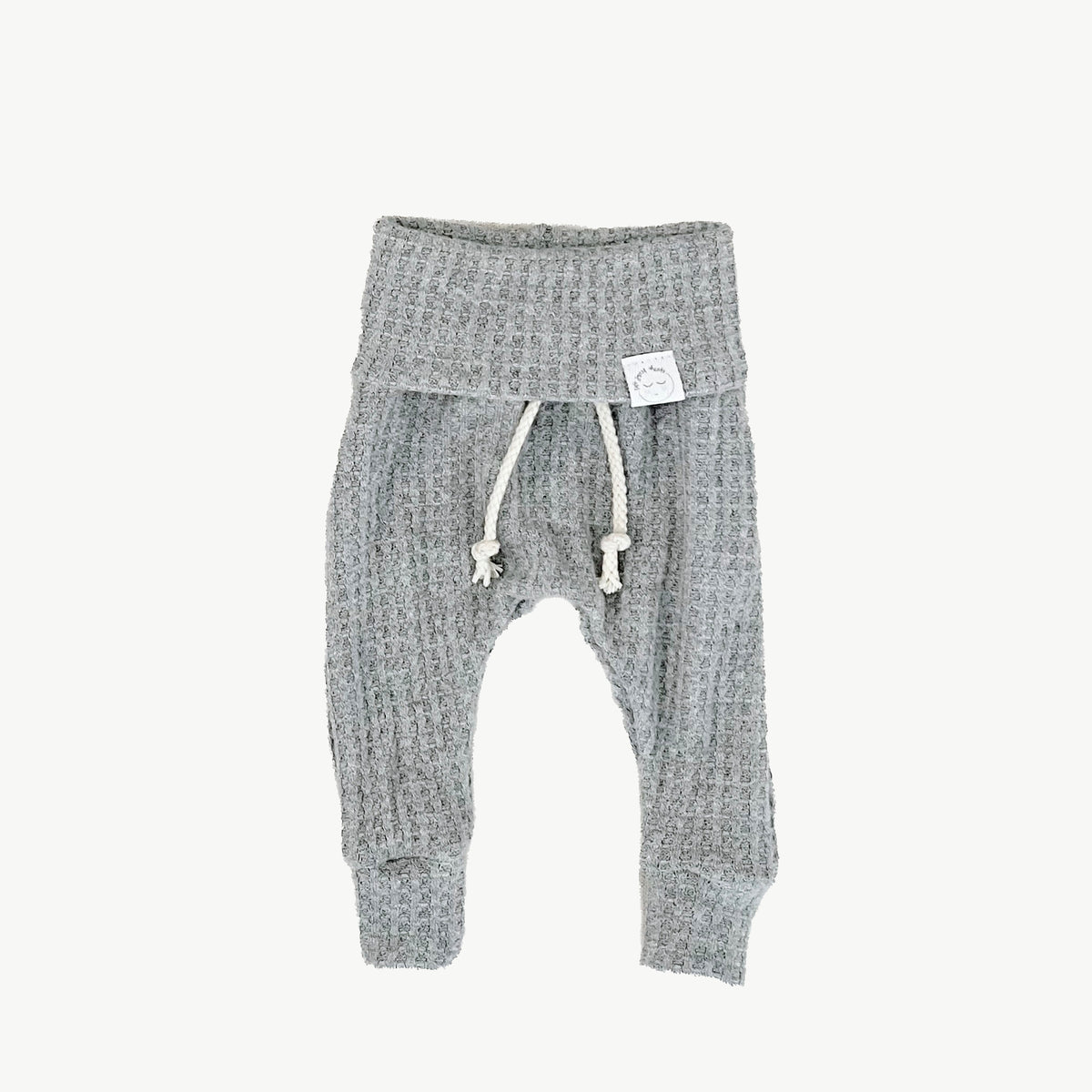 A pair of gray waffle-knit baby pants with a drawstring waist and ankle cuffs