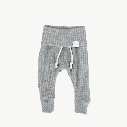 A pair of gray waffle-knit baby pants with a drawstring waist and ankle cuffs