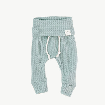 A pair of mint blue waffle-knit baby pants with a drawstring waist and ankle cuffs
