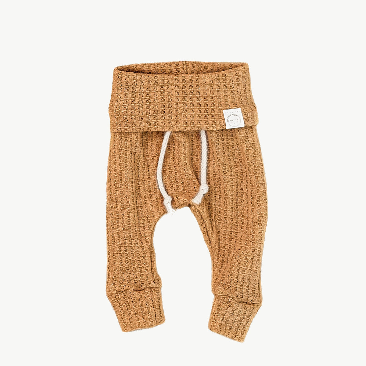 A pair of mustard waffle-knit baby pants with a drawstring waist and ankle cuffs
