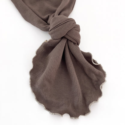 A close-up of a dark brown waffle-weave baby gown