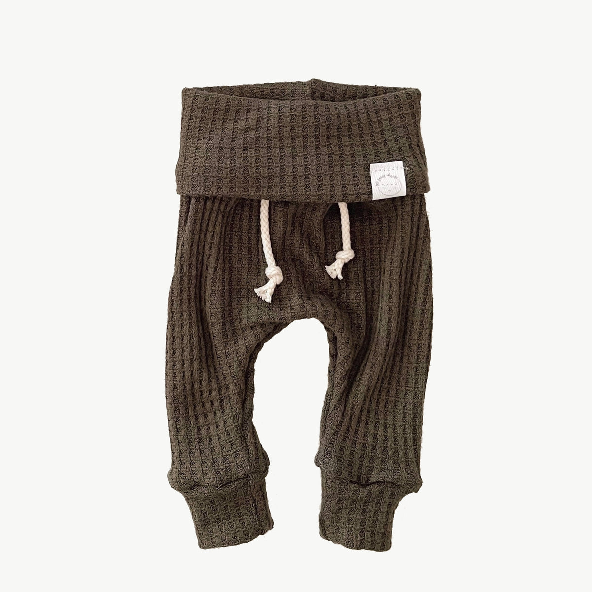 A pair of green waffle-knit baby pants with a drawstring waist and ankle cuffs