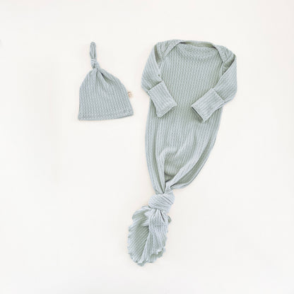 A baby knit set in a mint blue color, featuring a long-sleeve knotted gown and a matching knotted hat