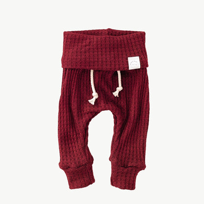 A pair of red waffle-knit baby pants with a drawstring waist and ankle cuffs