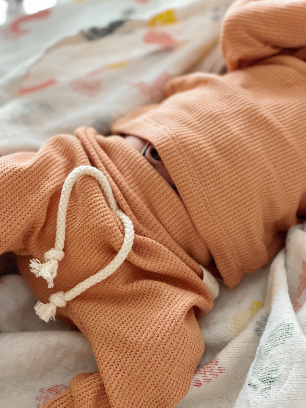 baby girl lying in a hospital bed with thermal peach color clothes