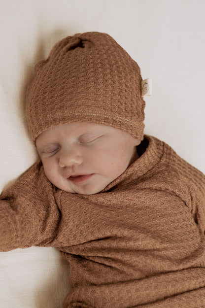 baby boy wearing a camel color waffle knit hat and long sleeve shirt