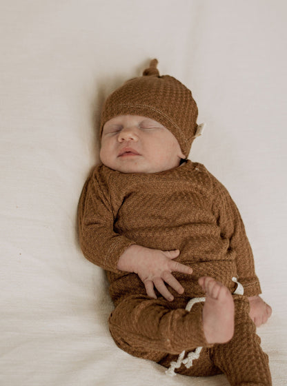 newborn baby boy wearing a soft brown waffle knit hat, long sleeve shirt and leggings