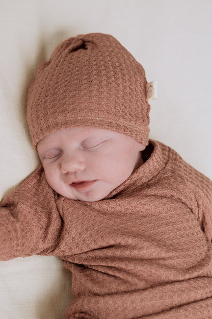 muted tone baby girl wearing waffle knit hat and shirt